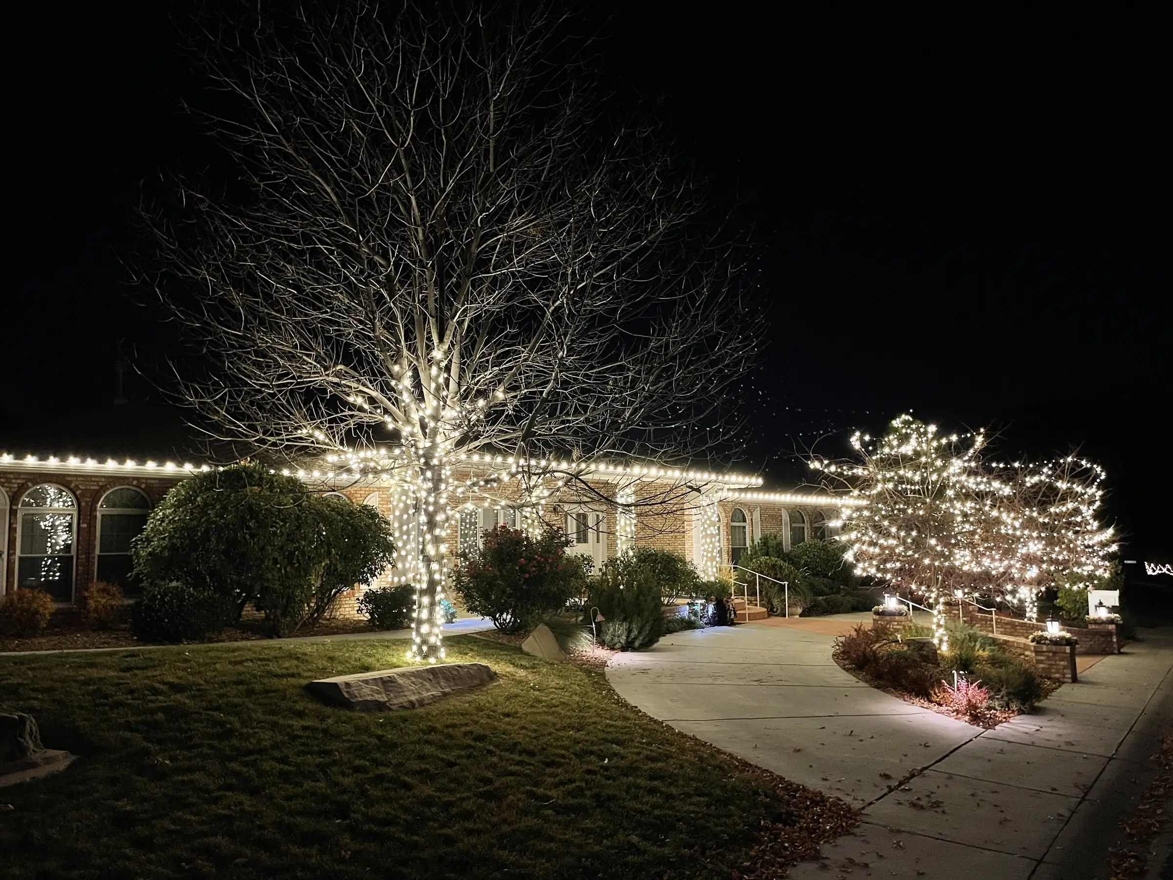 A home with warm roofline lights and a glowing walkway at blue hour